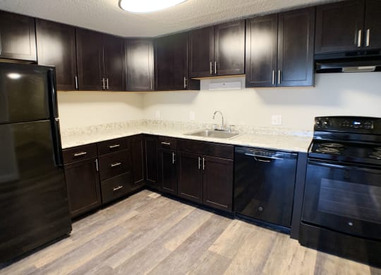 a kitchen with dark wood cabinets and a black refrigerator