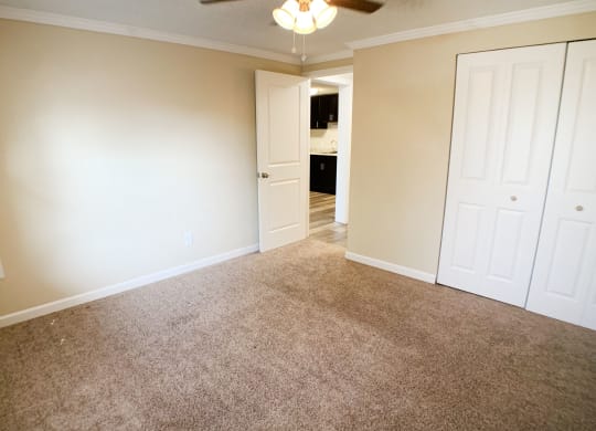 an empty living room with carpet and white doors