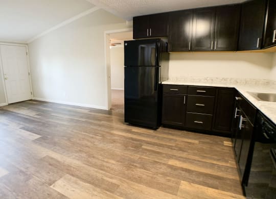 an empty kitchen with black appliances and wooden floors