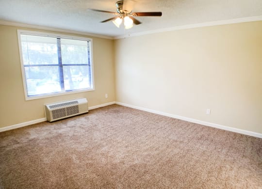 an empty living room with a window and a ceiling fan