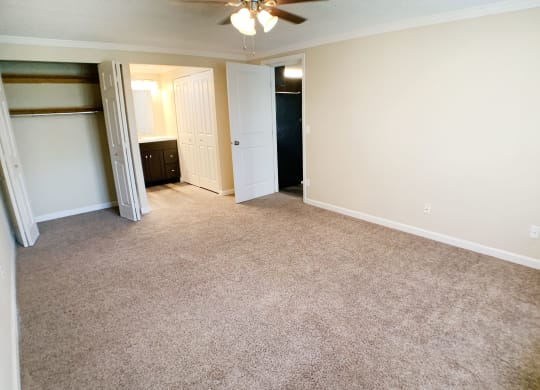 an empty living room with a closet and a ceiling fan