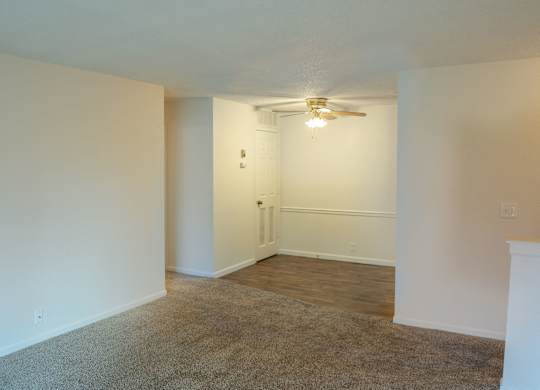 A room with a carpeted floor and a ceiling fan.