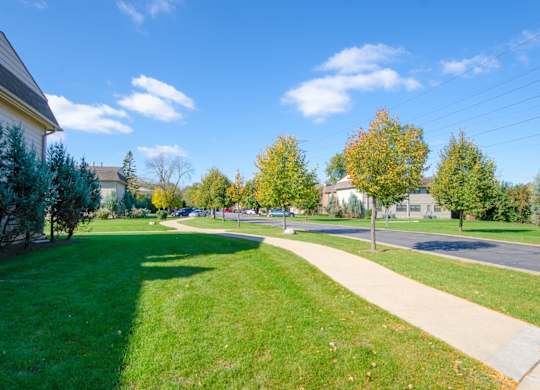 A sunny day in a residential area with houses, trees, and a clear blue sky.