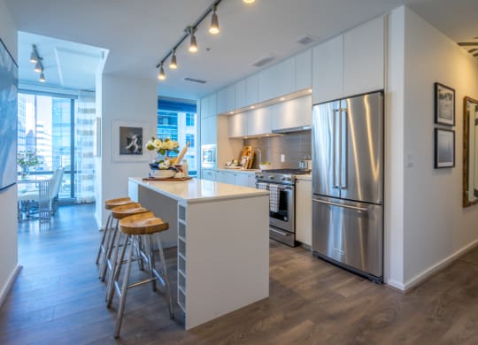 a kitchen with stainless steel appliances and a bar with three stools