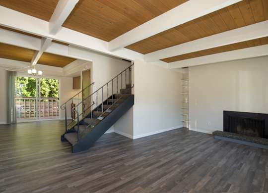 Spacious Living Room with Plank Flooring, Overhead Exposed Beams, Iron Staircase, and Fireplace at Woodlake Townhomes, Washington, 98026
