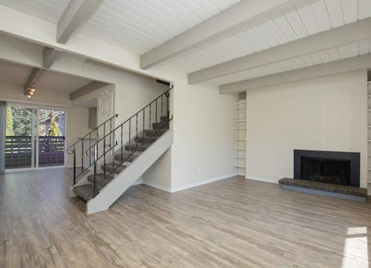 Newly Renovated Living Space with Exposed Ceiling Beams, Plank Flooring, a Staircase, and Fireplace at Woodlake Townhomes, Edmonds