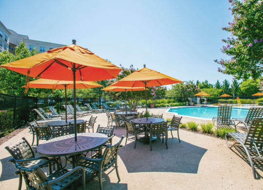 a patio with tables and umbrellas next to a swimming pool