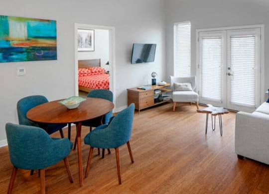 The Wilmore living room and dining room with table and chairs and tv over entertainment center