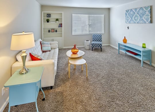 Large carpeted living space with window and staged with a couch, side tables, coffee table, chair and art.at Woodhaven, Everett, 98203