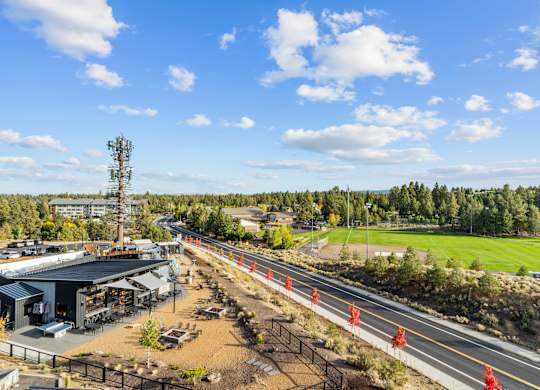 A road under construction with orange barriers and a clear blue sky.