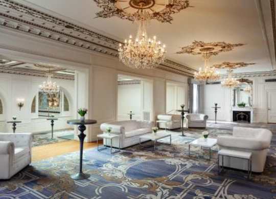 A luxurious living room with a chandelier, sofas, and a patterned rug.