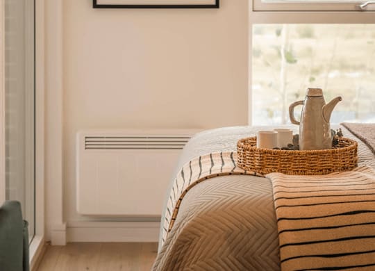 A framed artwork hangs on a wall above a bed with a basket on top of it. at Cherrywood Apartments, D18 VY3V
