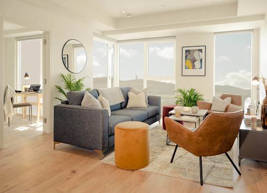 A living room with a grey couch, a brown chair, and a round mirror on the wall. at Cherrywood Apartments, D18 VY3V