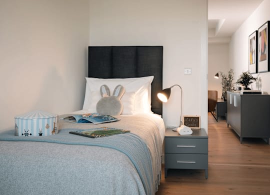 A bedroom with a bed, nightstand, and lamp. at Cherrywood Apartments, D18 VY3V