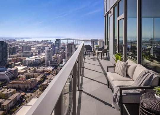 A balcony with a couch and chairs overlooking a cityscape.