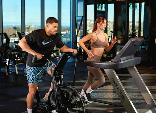 A man and a woman are exercising on elliptical machines in a gym at Cherrywood Apartments, D18 VY3V
