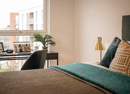 A bedroom with a bed, desk, and chair at Cherrywood Apartments, D18 VY3V