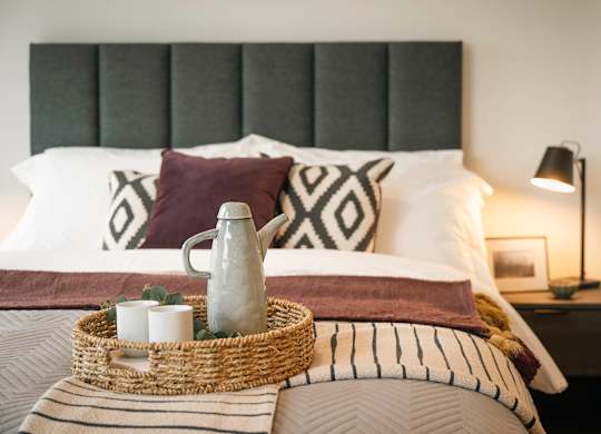 A bed with a wicker tray on top of it at Cherrywood Apartments, D18 VY3V