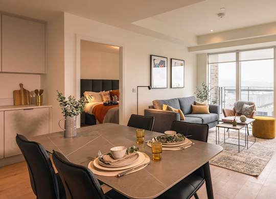 A dining room with a table set for two and a couch with a view of the city at Cherrywood Apartments, D18 VY3V