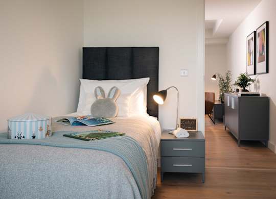 A bedroom with a bed, nightstand, and lamp at Cherrywood Apartments, D18 VY3V