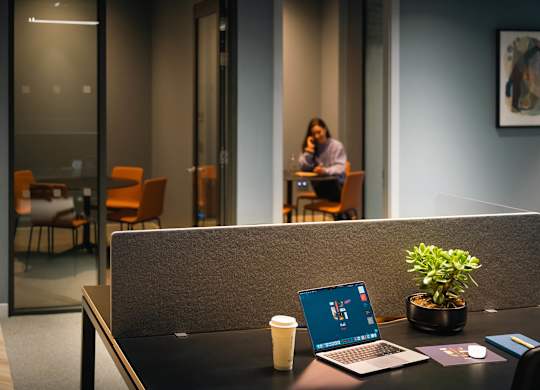 A laptop is open on a desk with a plant and a cup of coffee at Cherrywood Apartments, D18 VY3V
