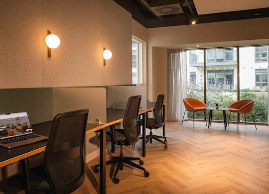 A laptop is open on a desk in a room with chairs and a window at Cherrywood Apartments, D18 VY3V