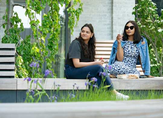 Two women sitting and having food in park at The Lark, London