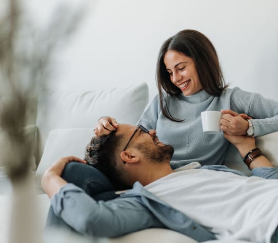a man laying in bed with a woman holding a cup of coffee