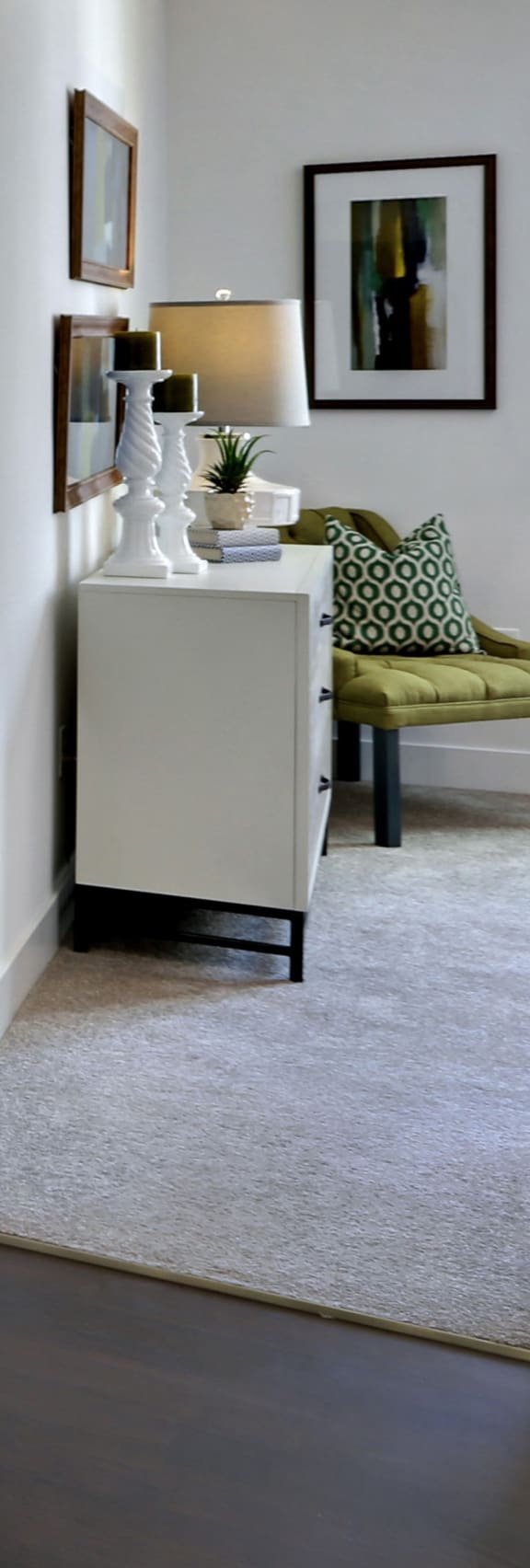 A white cabinet with a green cushioned chair and a white lamp on top of it. at West Park Apartments, San Diego, CA, 92108