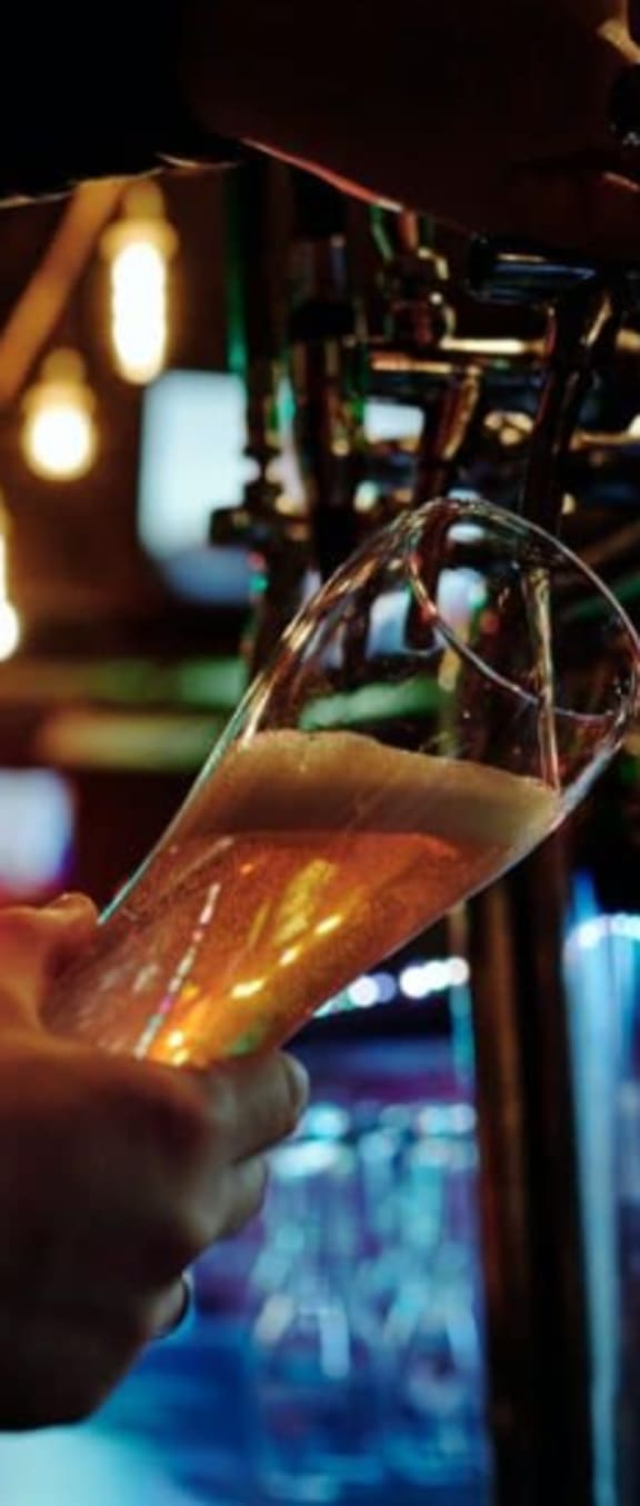 a person is holding a glass of beer
