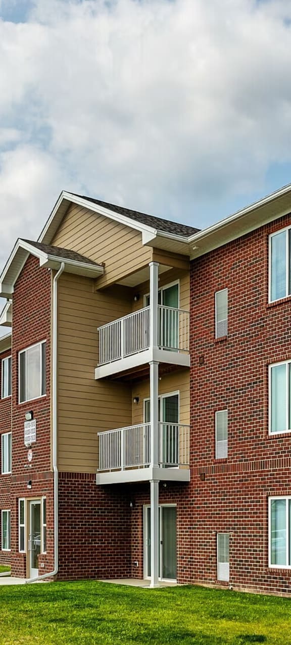 A red brick apartment building with a balcony on the second floor.