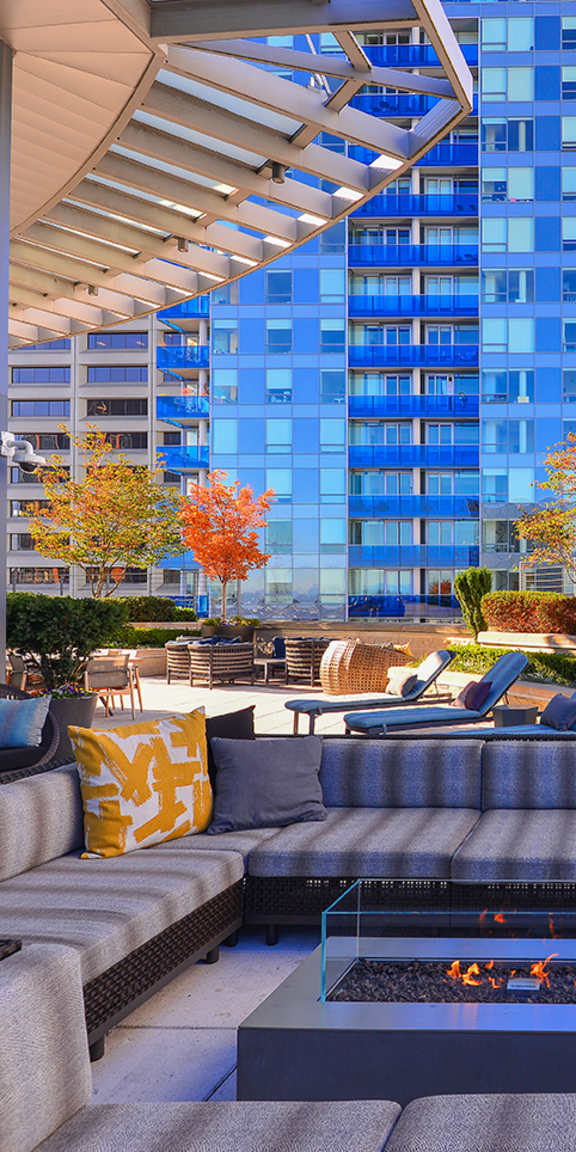 A patio with a fire pit and seating area with a view of a city skyline.