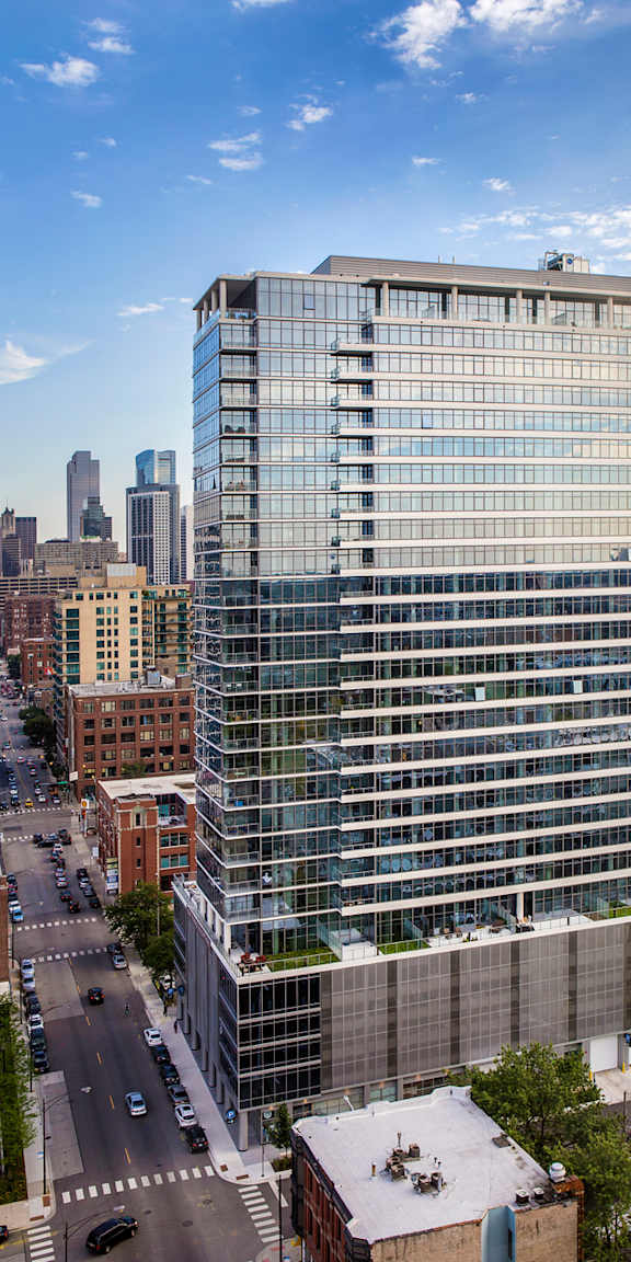 A tall glass building stands in the middle of a city street.