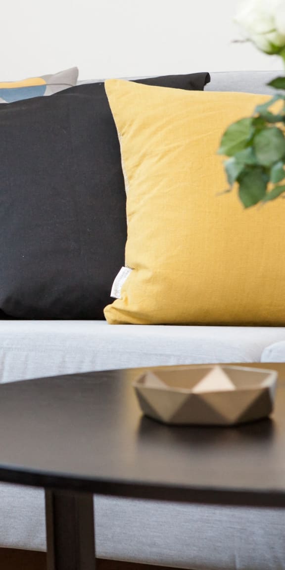 a living room with a couch and a table with a vase and some pill