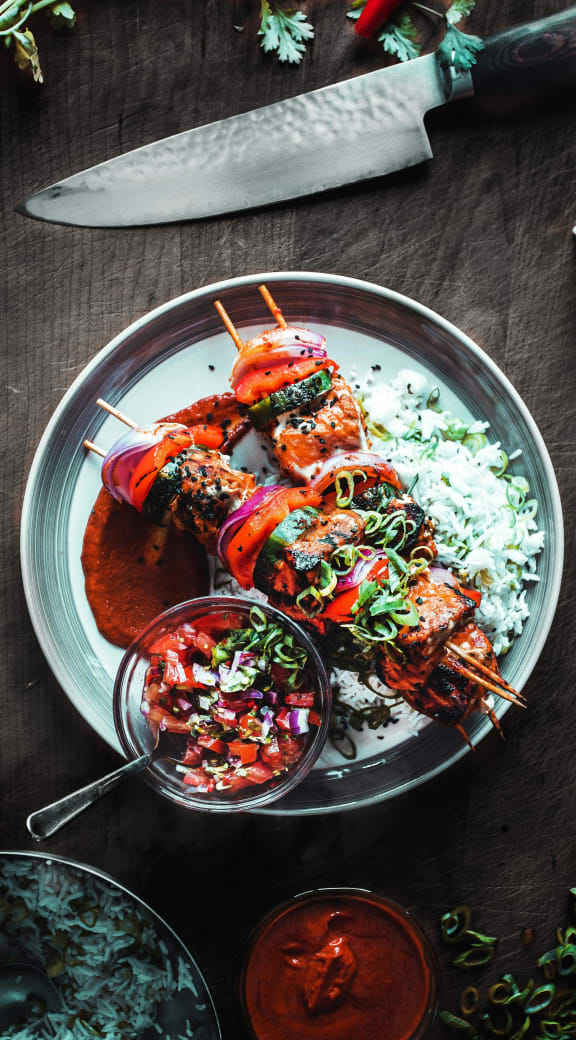 a plate of food with rice and chicken skewers and sauce