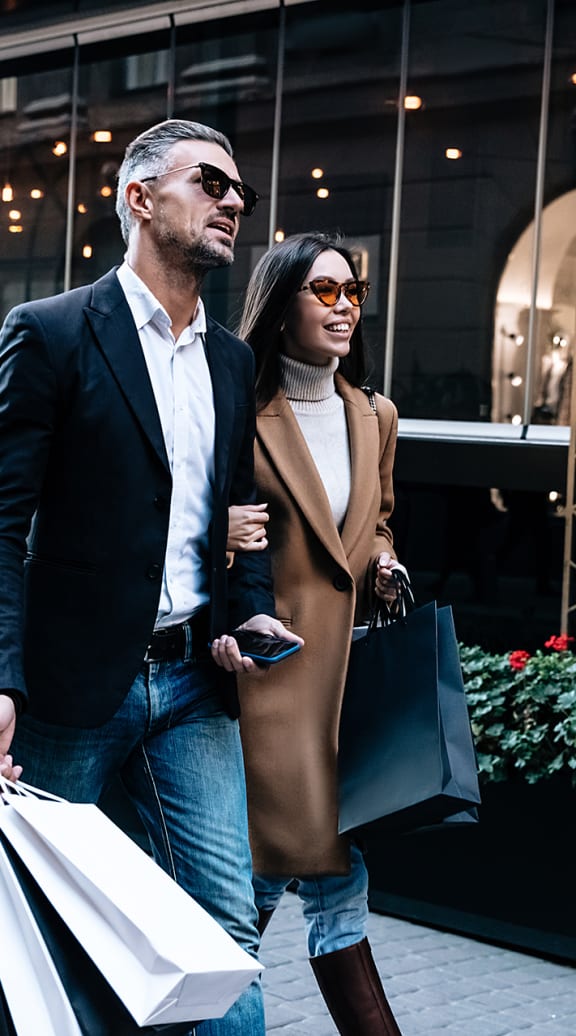 a man and woman walking down the street with shopping bags