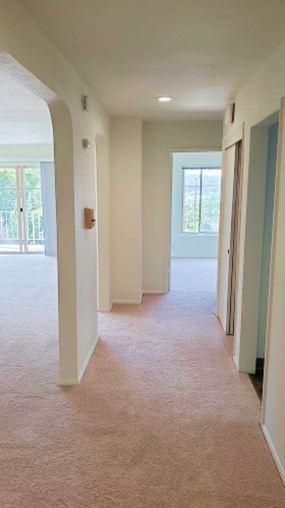 A long hallway with a carpeted floor and white walls.
