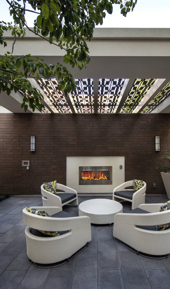 A patio with a fireplace and chairs. at West Park Apartments, San Diego, CA