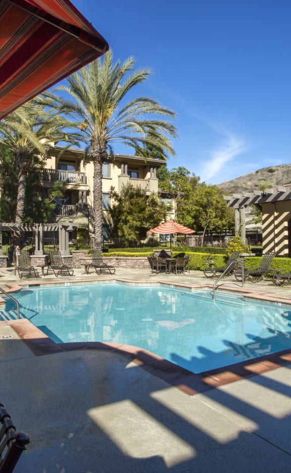 a resort style pool with lounge chairs and umbrellas at 55+ Remington at Ladera Ranch, Ladera Ranch, CA, 92694