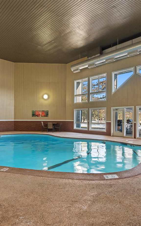 A large indoor swimming pool with a hot tub in the middle.