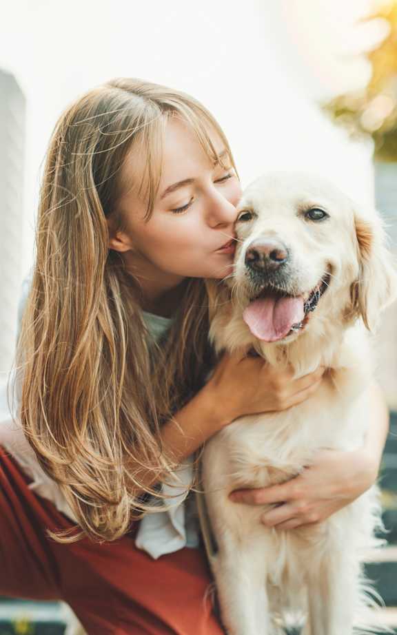 A woman is hugging a happy dog.