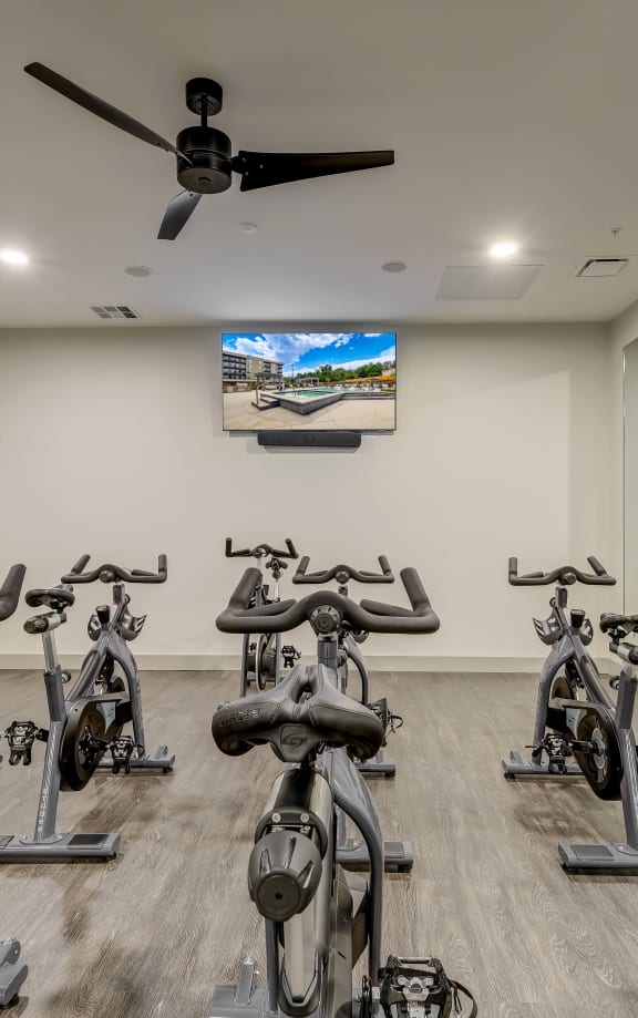 a room filled with spin bikes and a ceiling fan