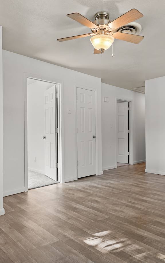 A room with a ceiling fan and wooden flooring.