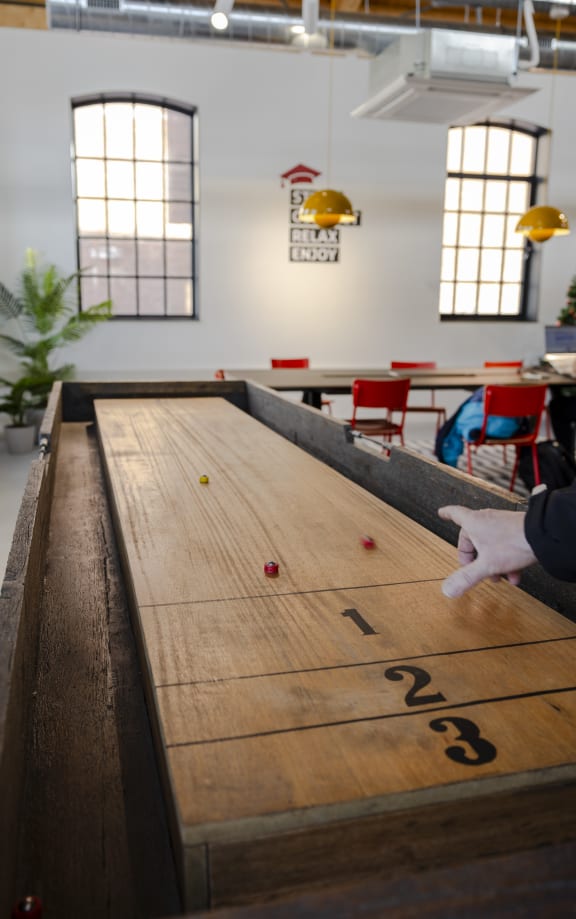 a man playing a game of shuffleboard on a wooden table
