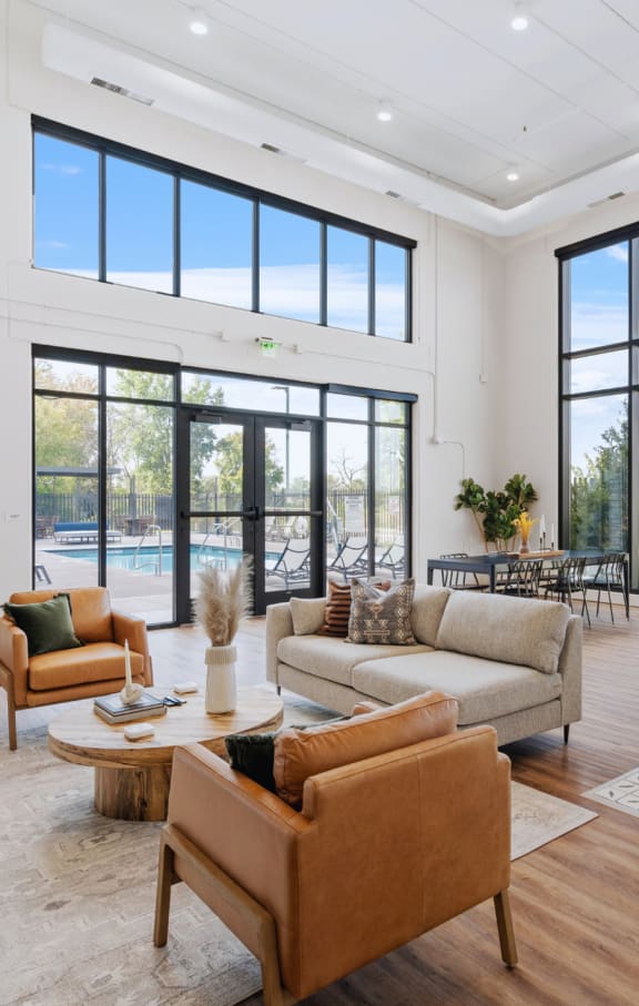 a large living room with a kitchen and a pool in the background