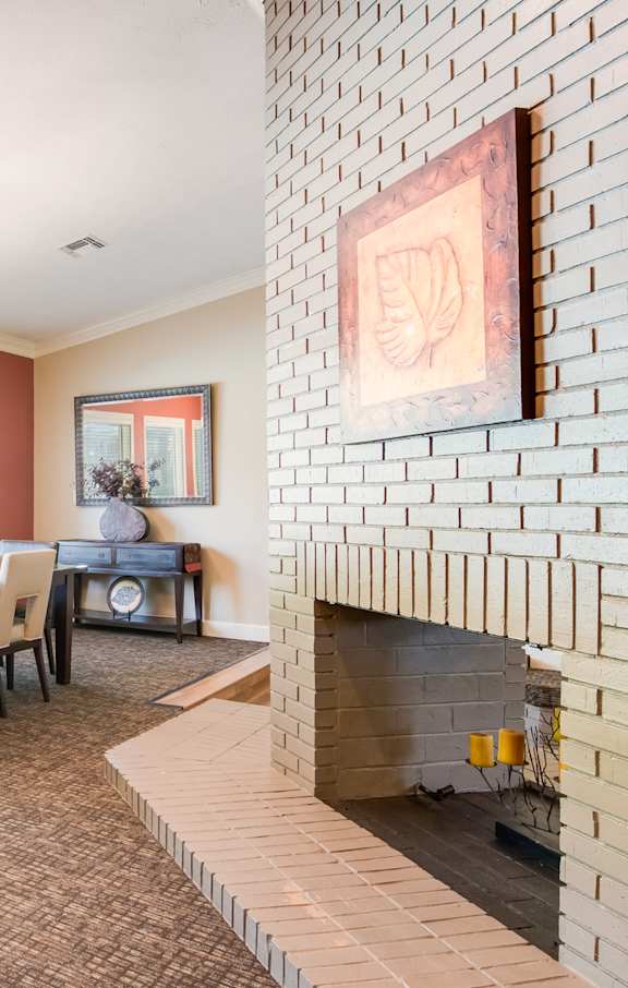 A dining room with a brick fireplace and a table set for four.