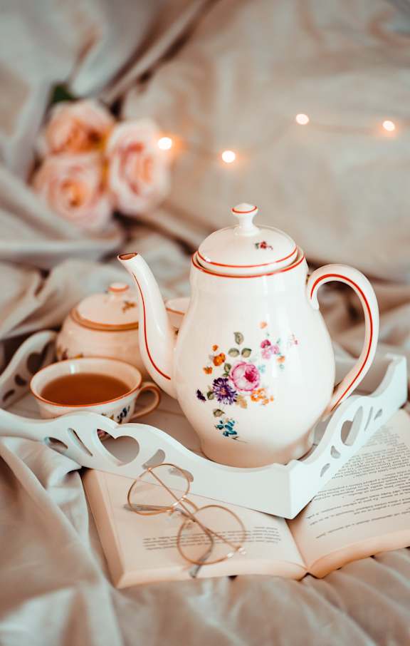 a cup of tea and a book on a bed