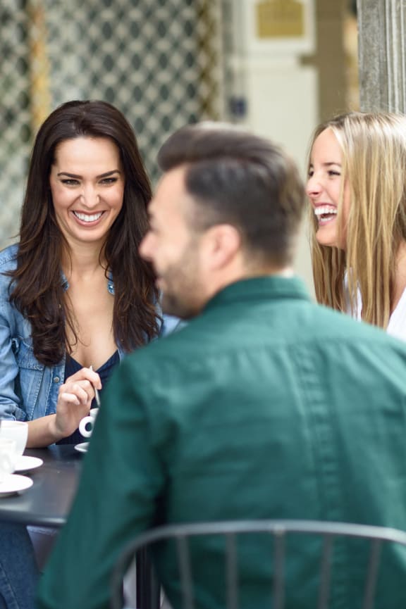 a group of people sitting at a table talking and laughing