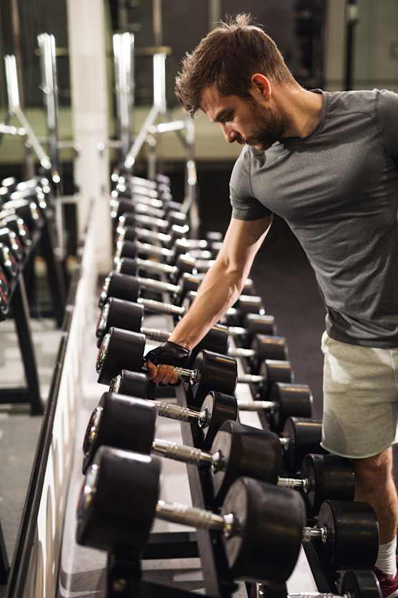 A man is working out with dumbbells in a gym.