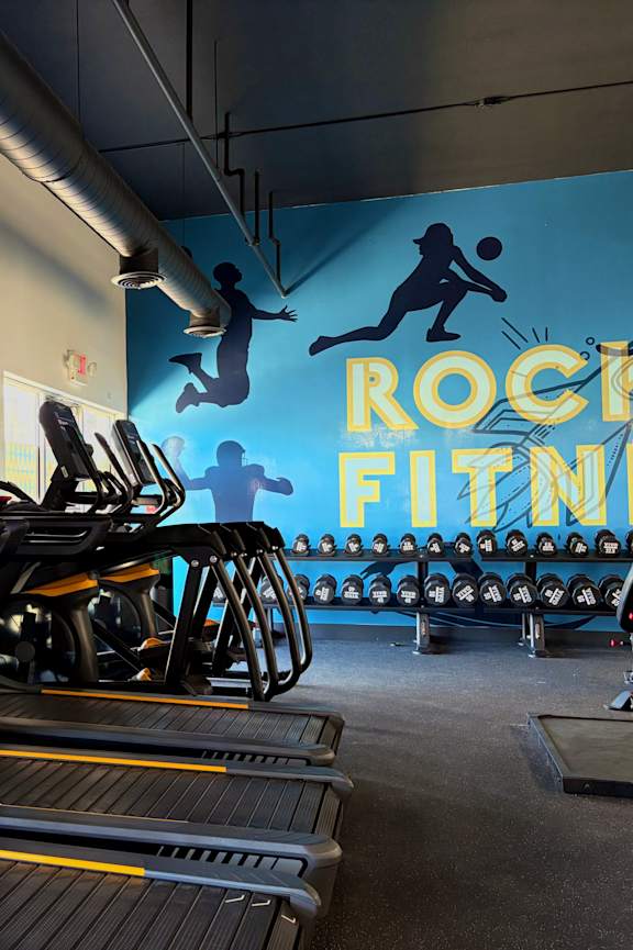 A gym with treadmills and a sign that says Rock Fitness.